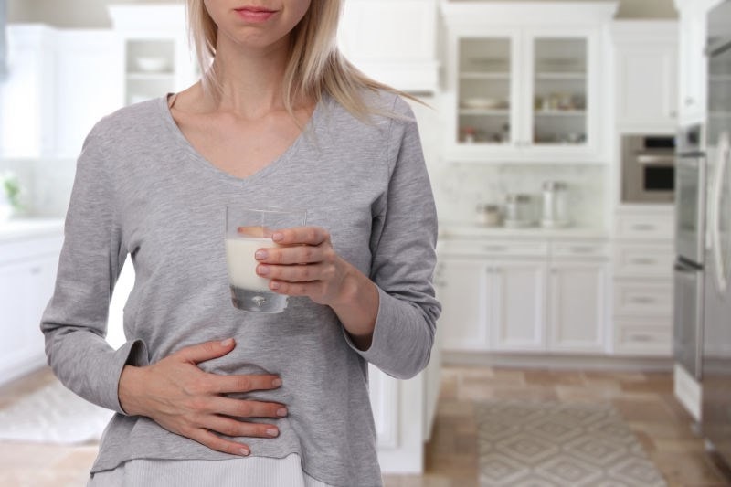 woman holding her tummy and glass milk