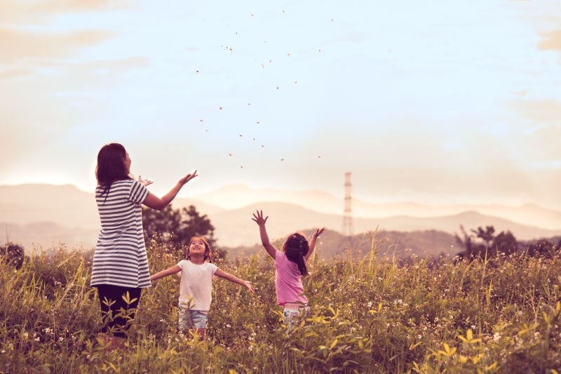 mother playing in field with daughters