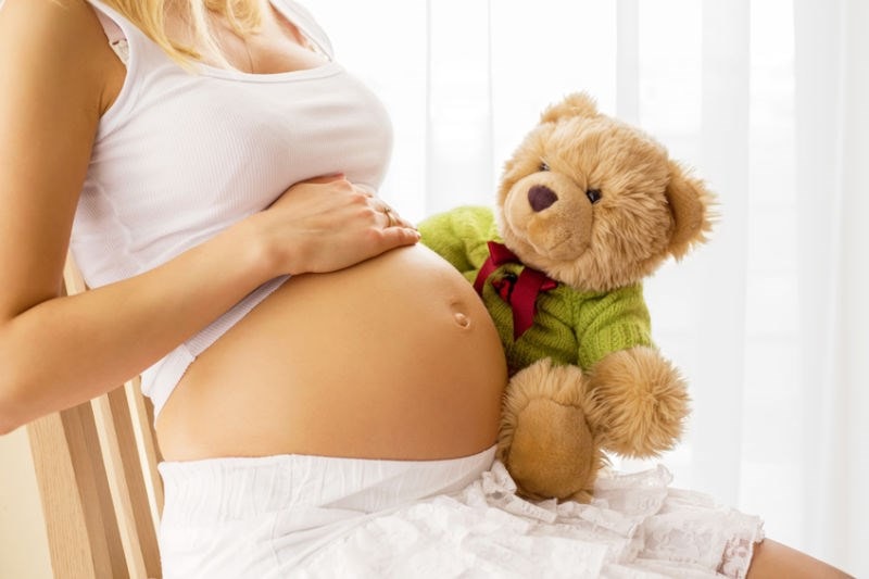 Pregnant woman sitting with teddy 