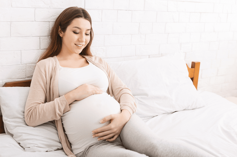 Happy pregnant woman with hand on bump