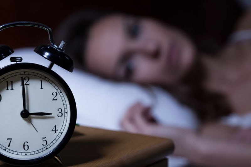 woman lying beside alarm clock 