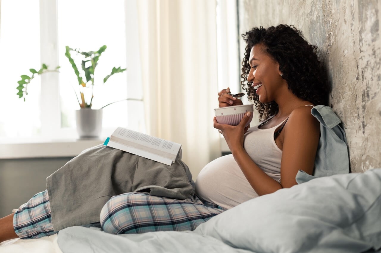 Pregnant woman smiling reading book