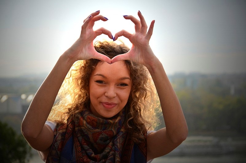Woman holding up hands in heart shape